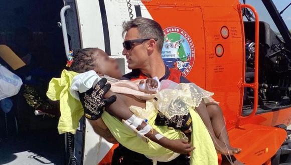 Un miembro de la tripulación aérea de la Guardia Costera que ayuda a transportar a un niño gravemente herido desde el helicóptero a los servicios médicos de emergencia en espera en Puerto Príncipe, Haití. (Foto de David STEELE / US COAST GUARD / AFP).