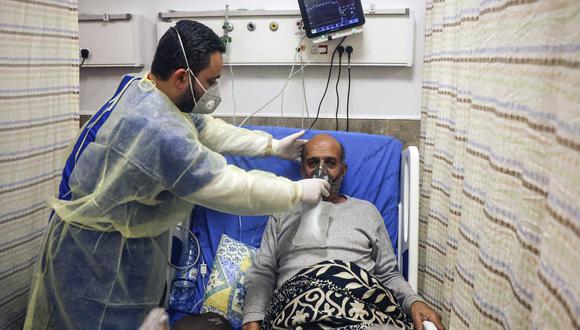 Un trabajador médico ajusta la máscara de respiración para un paciente en la sala de coronavirus del Hospital Gubernamental Dura. (Foto: HAZEM BADER / AFP)