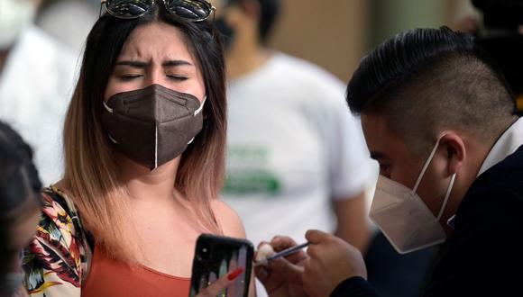 Una joven se toma una selfie mientras recibe una primera dosis de la vacuna AstraZeneca contra el coronavirus COVID-19 en la Ciudad de México, el 10 de agosto de 2021. (ALFREDO ESTRELLA / AFP).