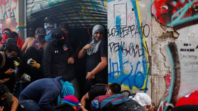 Manifestante se esconden de la policía chilena, en un local saqueado. (Foto: Reuters).