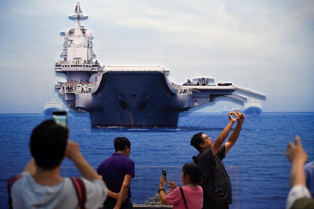A group takes a picture of the aircraft carrier Liaoning at an exhibition marking China's achievements over the past 70 years, on September 26, 2019.  (Photo by Wang Zhao/AFP)