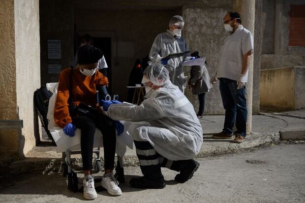 Bomberos franceses de Marins-Pompiers de Marsella con equipos de protección examinan a una mujer de 19 años, sospechosa de estar infectada con el nuevo coronavirus. (AFP/CHRISTOPHE SIMON).