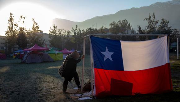 Un hombre rompe leña en un campo de fútbol donde se asentaron 90 personas exigiendo vivienda social, en Santiago de Chile, el 25 de julio de 2018. (Foto: CLAUDIO REYES / AFP).