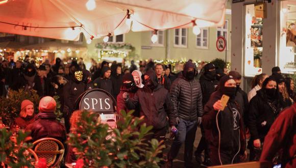 Miembros de Men In Black acosan a los clientes de un restaurante durante una protesta contra las nuevas restricciones contra el coronavirus en Copenhague, Dinamarca, el 20 de noviembre de 2021. (THIBAULT SAVARY / AFP).