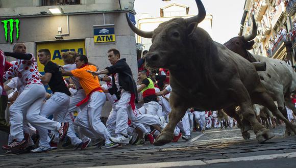 En esta foto de archivo tomada el 12 de julio de 2019, los participantes corren junto a toros de lidia y novillos en la sexta corrida de la fiesta de San Fermín en Pamplona, ​​norte de España. (Foto de JAIME REINA / AFP).