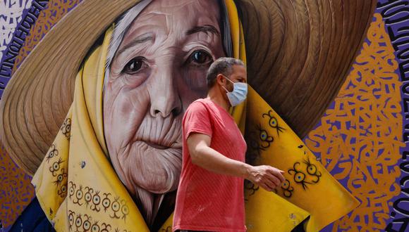 Un hombre que usa mascarilla pasa junto a un mural de arte mural en la ciudad de Ibiza, España, el 25 de mayo de 2021, en plena pandemia de coronavirus COVID-19. (David GANNON / AFP).