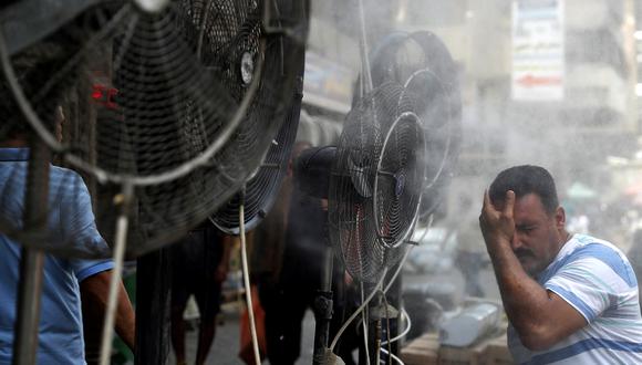Un hombre recibe aire de ventiladores que rocían aire mezclado con vapor de agua desplegado por donantes para enfriar a los peatones a lo largo de una calle en la capital de Irak, Bagdad, el 30 de junio de 2021 en medio de una fuerte ola de calor. (Foto: AHMAD AL-RUBAYE / AFP)