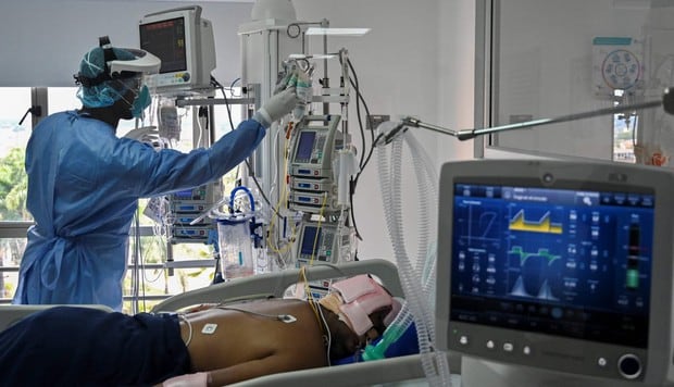 Un empleado del hospital con equipo de protección atiende a un presunto paciente con COVID-19 en la unidad de cuidados intensivos de una clínica en Colombia. (AFP / Luis ROBAYO).