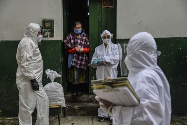 Los trabajadores de la Alcaldía de Bogotá usan trajes protectores para evitar infectarse con COVID-19, mientras realizan un censo en el vecindario de Egipto en Bogotá para saber cuántas familias deben recibir alimentos (Foto: Diana Sánchez / AFP)