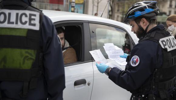 Un policía francés verifica que un automovilista lleve el documento de movilidad correcto en la Place d'Italie en París. (Foto: AFP).