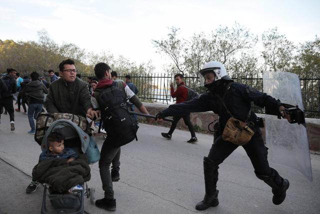 Un policía antidisturbios golpea a un migrante con su porra mientras la policía intenta dispersar a un grupo de migrantes fuera del puerto de Mitilene, Grecia. (Foto: Reuters)