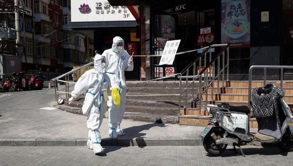 Trabajadores de la salud con trajes de protección caminan por una carretera en el distrito de Chaoyang en Beijing, China.