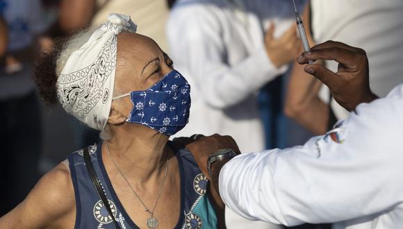 Un trabajador de la salud muestra la jeringa a una mujer después de inyectarle una dosis de la vacuna Sinovac, en Duque de Caxias, Brasil, el miércoles 24 de marzo de 2021.  (AP/Silvia Izquierdo).