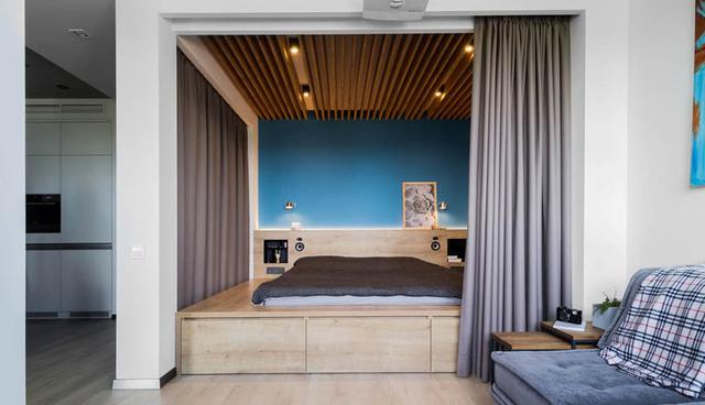 La habitación está junto a la sala y la cama está colocada sobre un tabladillo de madera. A diferencia de los demás espacios, este ambiente tiene una pared azul en degradé, que genera un efecto de profundidad. (Foto: vae.by)