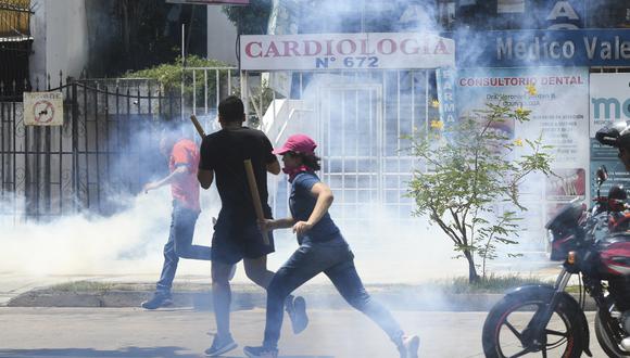 Los manifestantes huyen de los gases lacrimógenos lanzados por la policía antidisturbios durante una protesta para exigir un censo para 2023 en Santa Cruz, Bolivia.