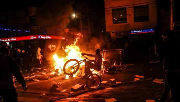 Imagen referencial. Un manifestante monta una bicicleta en una barricada incendiada durante los enfrentamientos con la policía en Bogotá (Colombia). Protestas en el país dejan al menos 8 muertos. (AFP / STR).