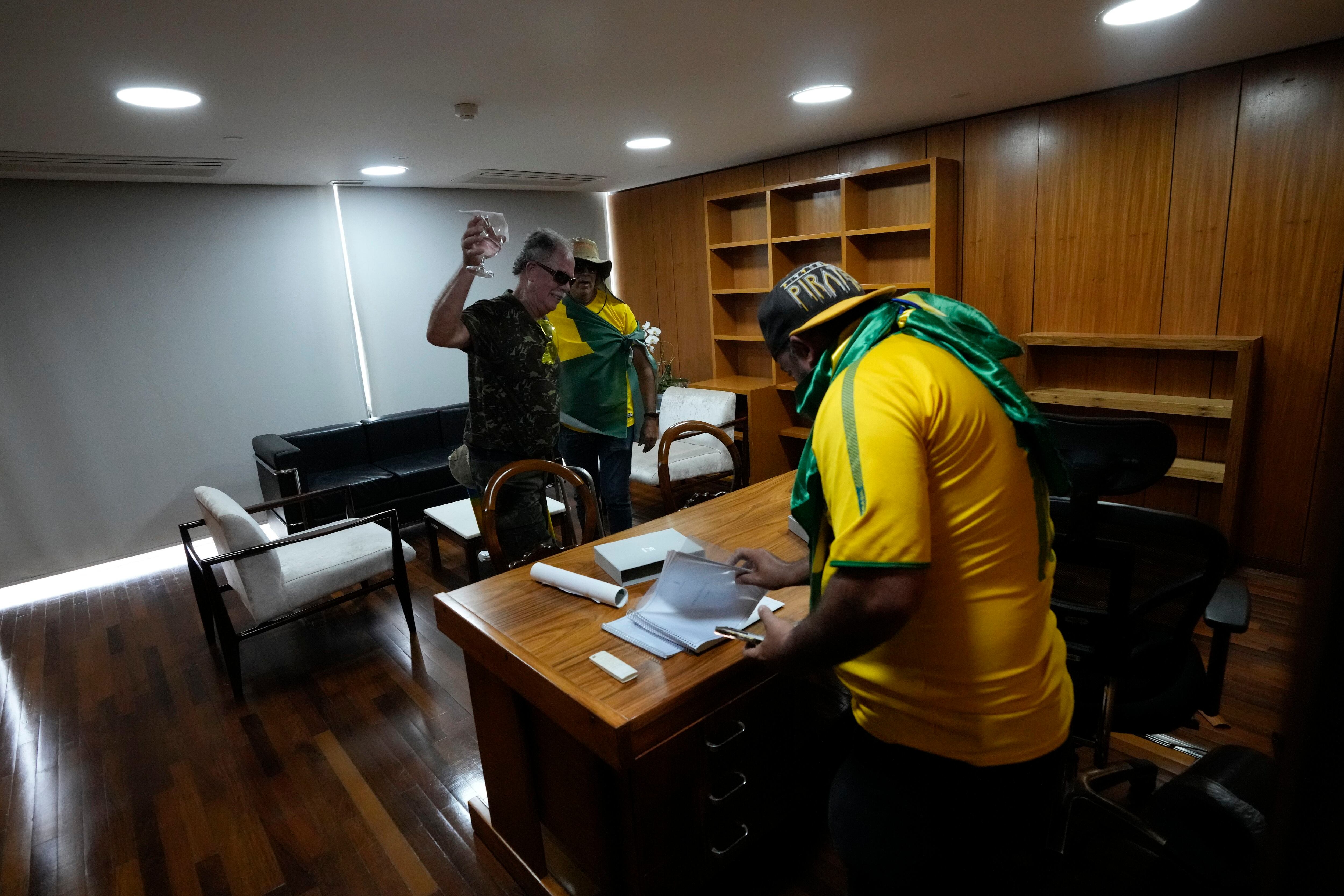 Protesters, supporters of former Brazilian President Jair Bolsonaro, go through papers on a desk after storming the Planalto Palace in Brasilia, Brazil.