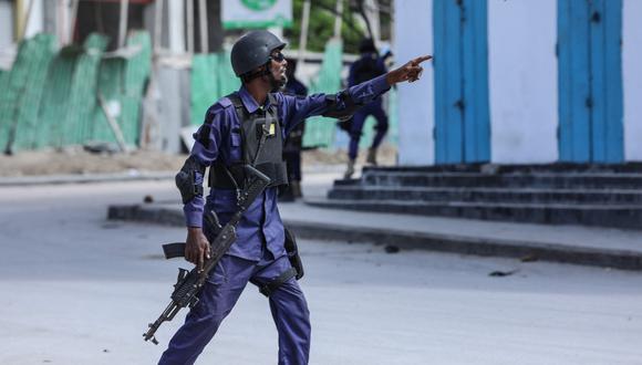Un oficial de seguridad hace gestos mientras él y sus colegas patrullan el lugar de las explosiones en Mogadiscio.