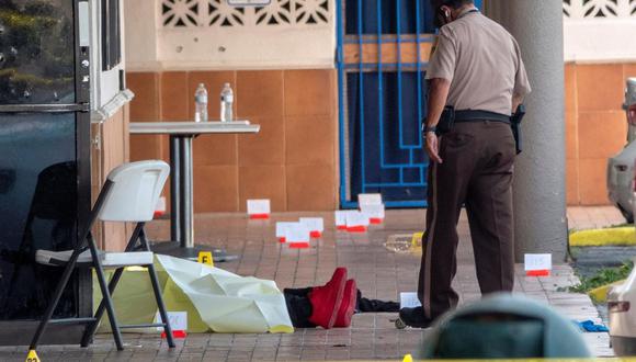 Un oficial de policía revisa el cuerpo de una víctima de un tiroteo, en la entrada del salón de banquetes Billiards en Miami Gardens, Florida, Estados Unidos. (EFE / EPA / CRISTOBAL HERRERA-ULASHKEVICH).