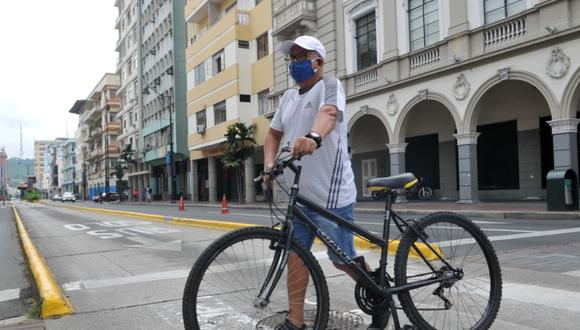 Un hombre camina con una bicicleta con una máscara facial en Guayaquil, Ecuador.