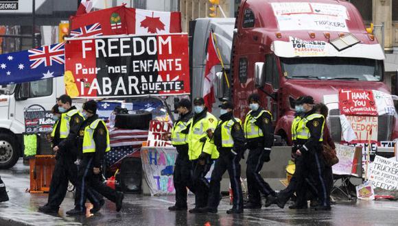 Oficiales de la Policía Provincial de Ontario caminan frente a la protesta de bloqueo de camioneros en curso en Ottawa. (Foto: Adrian Wyld/The Canadian Press vía AP).
