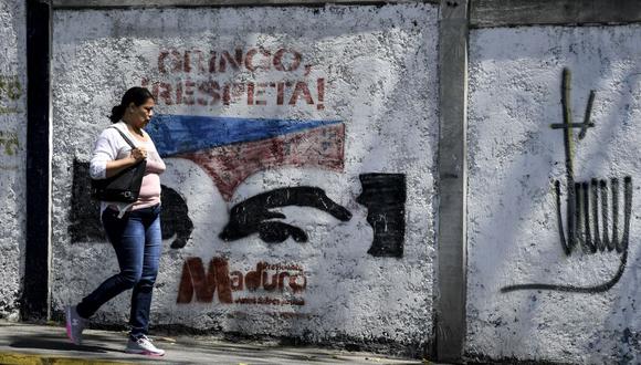Una venezolana pasa junto a un grafiti que dice "¡Gringo, Respeta!" sobre una representación de los ojos del fallecido presidente Hugo Chávez, en Caracas el 5 de febrero de 2020. (Foto de Yuri CORTEZ / AFP).