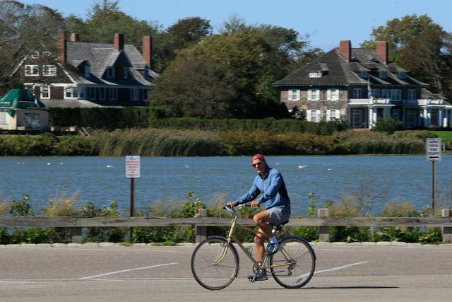 Un hombre anda en bicicleta cerca de la playa en Southampton, Nueva York. Las sombrillas de playa están en los garajes traseros cuando las temperaturas bajan, pero los neoyorquinos adinerados se quedan en los Hamptons más allá del verano, temerosos de la pandemia y el aumento de la delincuencia. (AFP / Kena Betancur).