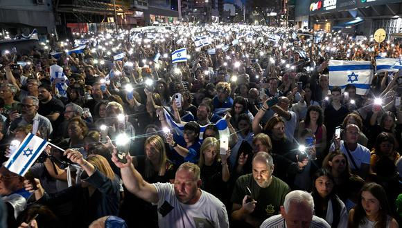 Gente sostiene banderas nacionales israelíes y muestra sus teléfonos móviles encendidos durante una manifestación en apoyo del pueblo de Israel, en Buenos Aires el 9 de octubre de 2023. (Foto de Luis ROBAYO / AFP)