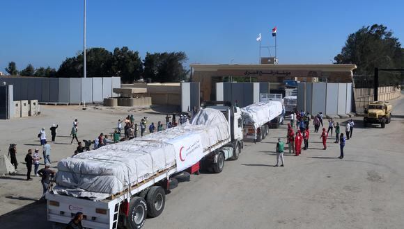 La gente en el lado egipcio del cruce fronterizo de Rafah observa cómo un convoy de camiones que transportan ayuda humanitaria cruza hacia la Franja de Gaza el 21 de octubre de 2023. (Foto de Mohammed Assad / AFP)