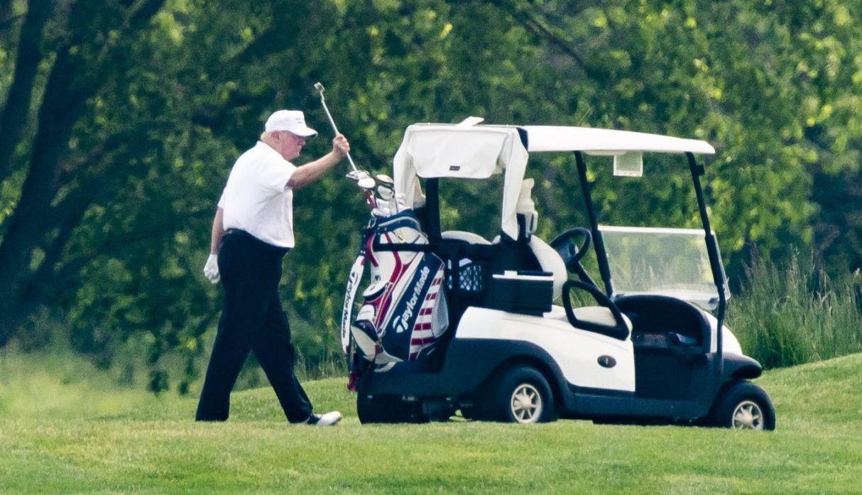 El presidente de Estados Unidos, Donald Trump, con un sombrero y una camisa polo blanca, juega al golf en el Trump National Golf Club en Sterling, Virginia. (EFE/EPA/JIM LO SCALZO).