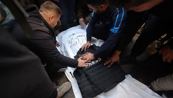 Compañeros periodistas lloran ante el cuerpo de Mustafa Thuria, redactor de vídeos de la agencia de noticias AFP, que murió en un presunto ataque aéreo israelí durante su funeral en Rafah, en la Franja de Gaza, el 7 de enero de 2024. (Foto de AFP)