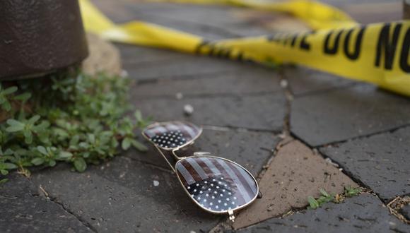 La cinta policial sobre el crimen se ve cerca de unas gafas de sol con el tema de la bandera estadounidense tiradas en el suelo en la escena del tiroteo del desfile del 4 de julio en Highland Park, Illinois, el 4 de julio de 2022. (Foto referencial de Youngrae Kim / AFP)