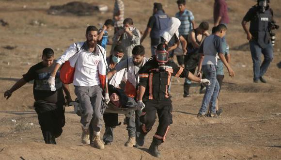 Activistas palestinos intentan auxiliar a un sujeto herido en la Franja de Gaza. (Foto referencial: AFP)