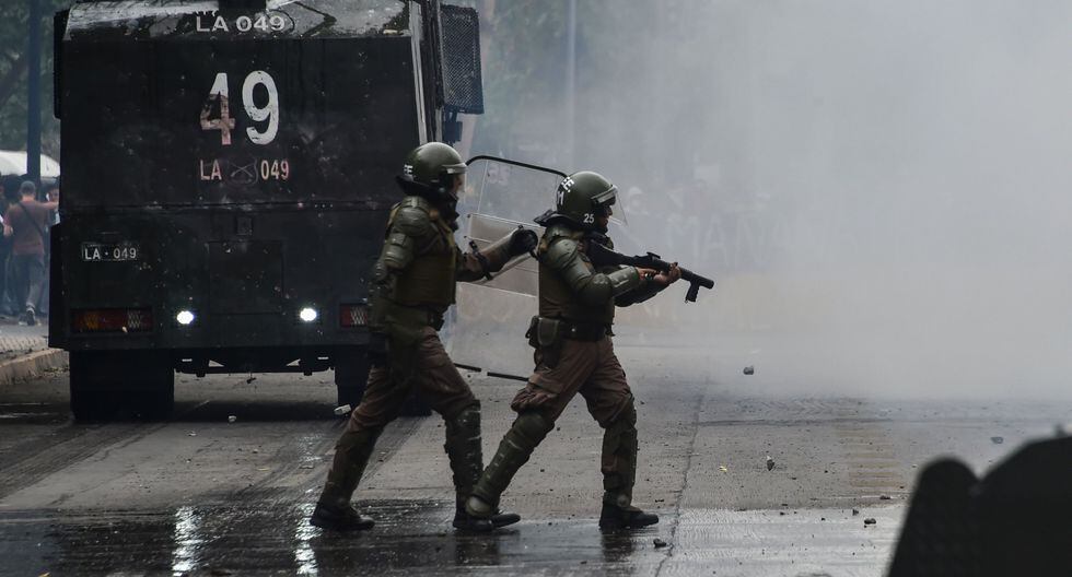 La policía antidisturbios confronta a los manifestantes que protestan contra las políticas económicas del gobierno del presidente Sebastián Piñera en Santiago. (AFP / Rodrigo ARANGUA).