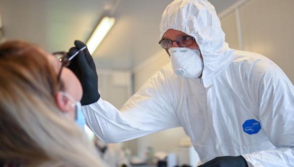 Un empleado de una organización de ayuda toma una muestra a una mujer en una estación de pruebas de coronavirus en Dortmund, Alemania. (Foto: Ina FASSBENDER / AFP).