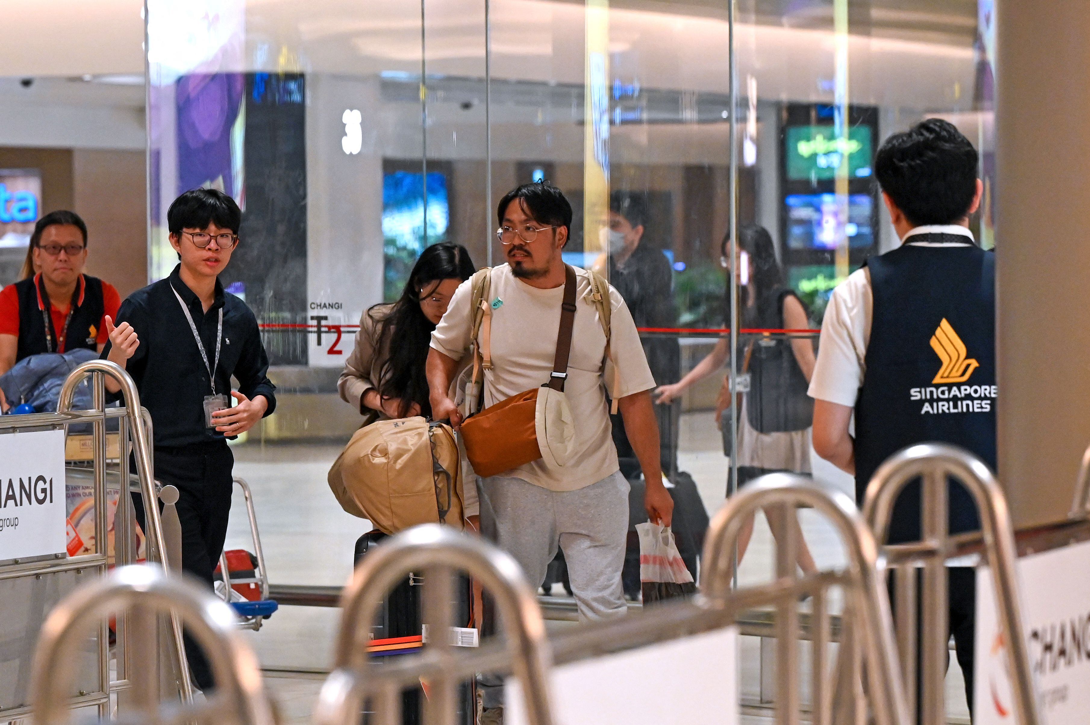 Los pasajeros del vuelo SQ321 de Singapore Airlines de Londres a Singapur, que realizó un aterrizaje de emergencia en Bangkok, son escoltados por personal de tierra a su llegada al aeropuerto Changi de Singapur el 22 de mayo de 2024. (Foto de Roslan RAHMAN / AFP)