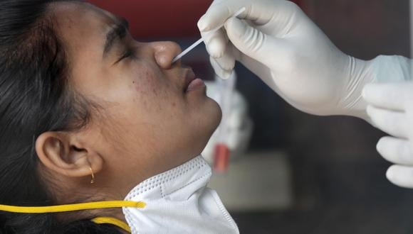 Un trabajador de la salud recoge una muestra de hisopo para la prueba de coronavirus COVID-19 de una persona en un hospital gubernamental en Calcuta, India, el 27 de enero de 2022. (EFE/EPA/PIYAL ADHIKARY).
