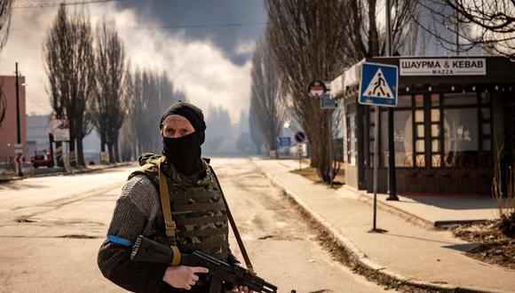 Un militar ucraniano hace guardia cerca de un almacén en llamas alcanzado por un proyectil ruso en los suburbios de Kiev el 24 de marzo de 2022.
(FADEL SENNA / AFP)