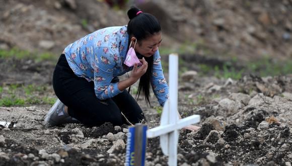 Una mujer llora junto a la tumba de su abuela, víctima de la nueva pandemia de coronavirus, en el cementerio "Covid-19", en Tegucigalpa, el 2 de noviembre de 2020. (Orlando SIERRA / AFP).