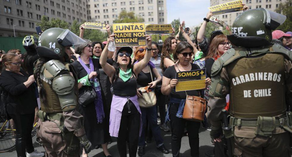 Feminist activists protest outside La Moneda government Palace in Santiago, Chile, Friday, Oct. 25, 2019. A new round of clashes and looting broke out Thursday as demonstrators returned to the streets, dissatisfied with economic concessions announced by the government in a bid to curb a week of deadly violence. (AP Photo/Rodrigo Abd)