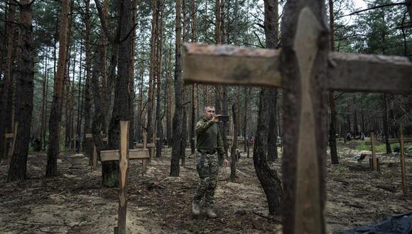 Oleg Kotenko, comisionado encargado de cuestiones relacionadas con desapariciones en circunstancias especiales, usa su smartphone para grabar tumbas no identificados de civiles y soldados ucranianos en la zona de Izium, Ucrania. (Foto AP/Evgeniy Maloletka)