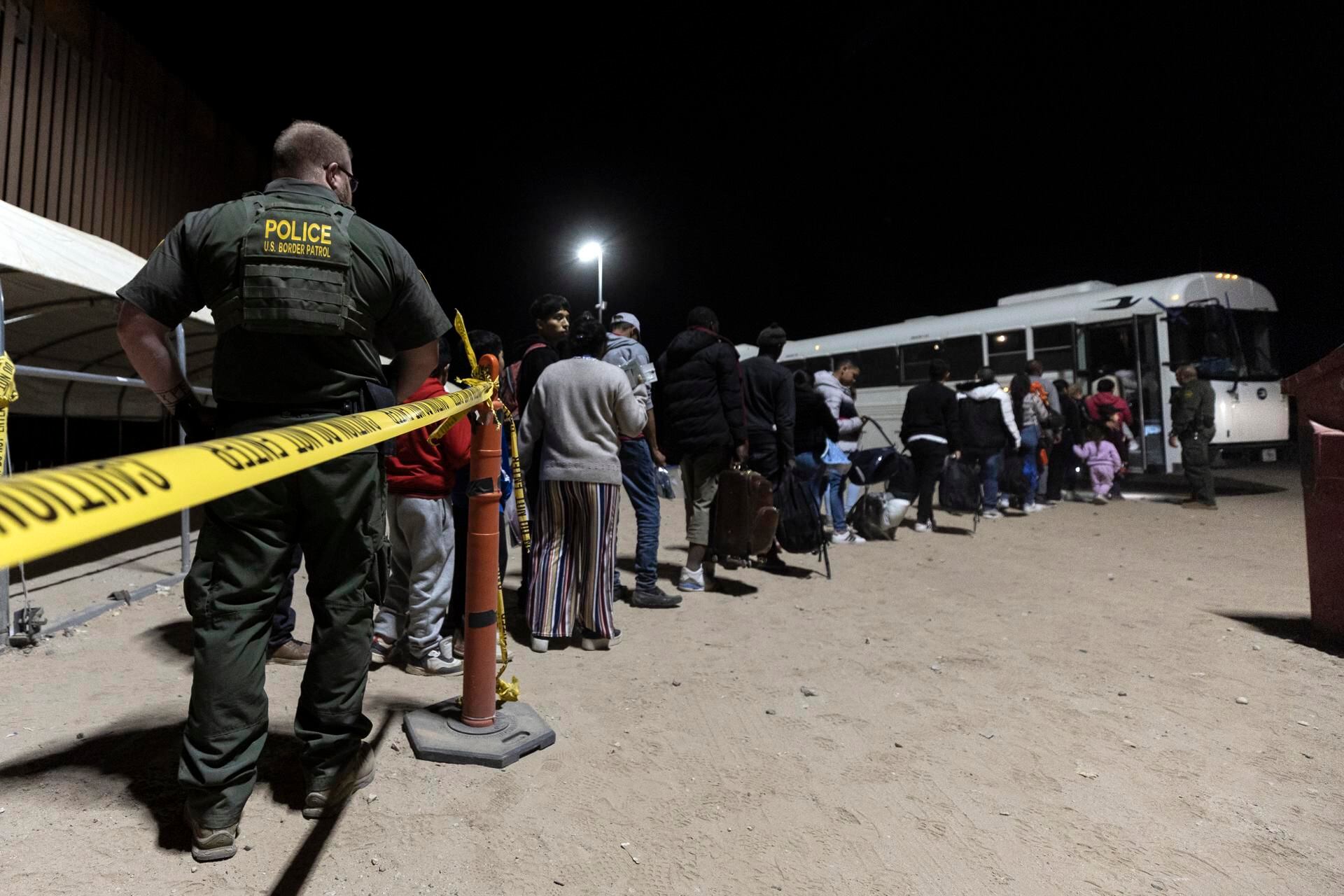 Migrants walk towards a bus that will take them to a processing center after illegally crossing into the United States in Yuma, Arizona, May 11, 2023. (EFE/EPA/ETIENNE LAURENT).