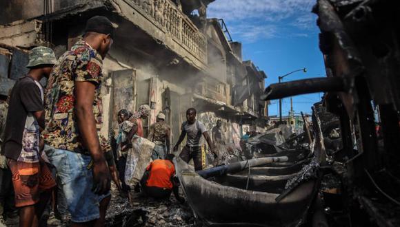 Hombres recogen piezas de aluminio en el lugar donde explotó un camión cisterna en Cap-Haitien, Haití, el 14 de diciembre de 2021. (Foto: Richard Pierrin / AFP)