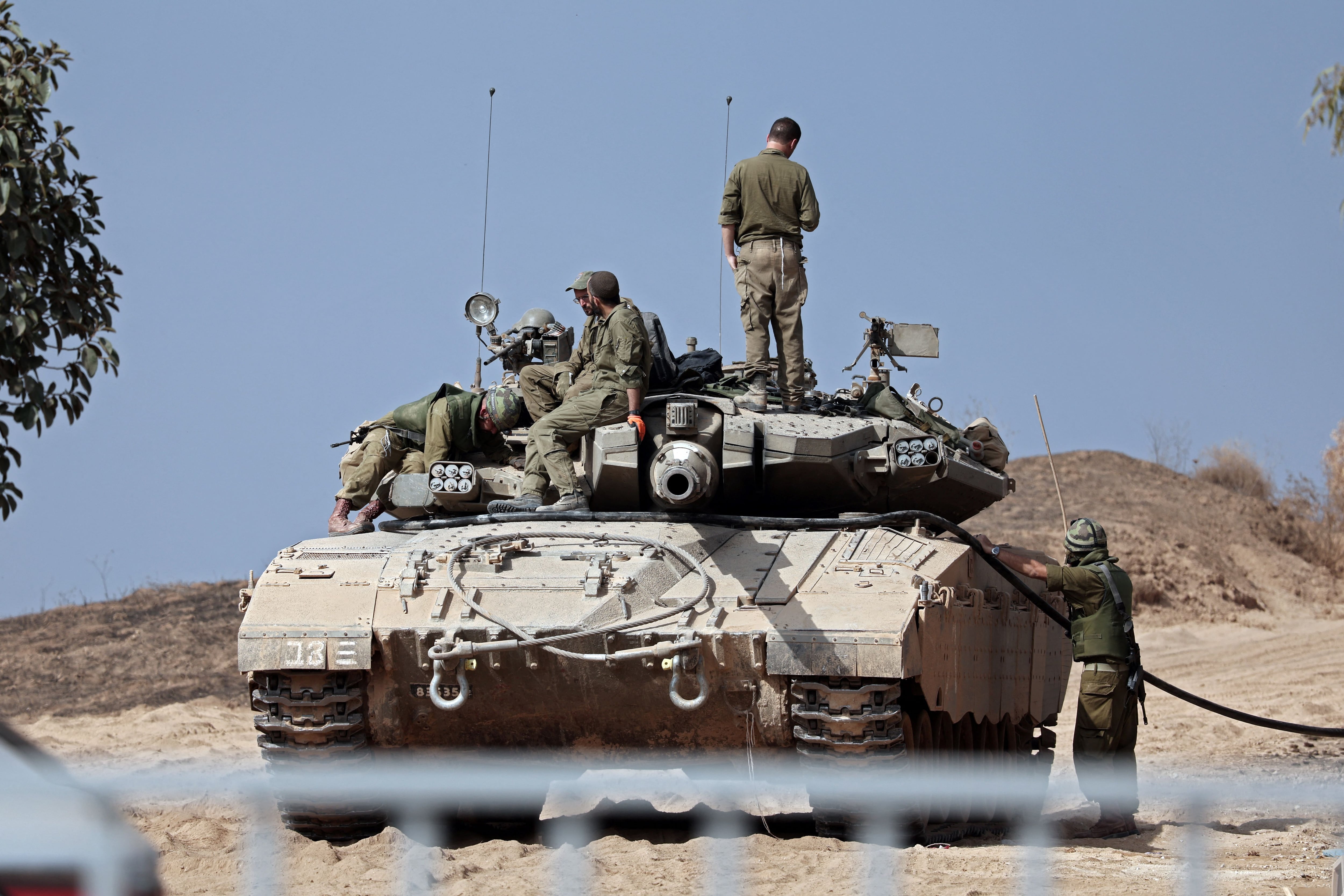Israeli soldiers refuel their Merkava tank near the city of Sderot, southern Israel, on October 23, 2023. (Photo by Thomas COEX/AFP).