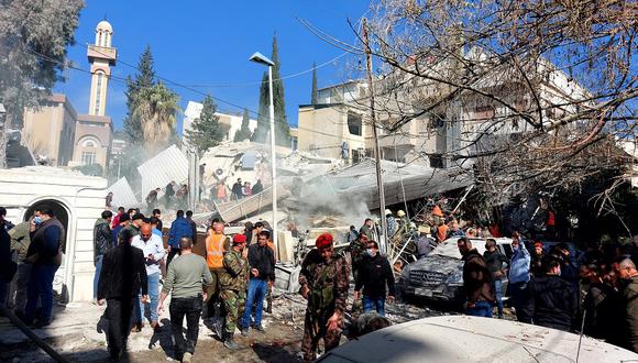 Gente y las fuerzas de seguridad se reúnen frente a un edificio destruido en un ataque israelí en Damasco el 20 de enero de 2024. (Foto de Louai Beshara / AFP)