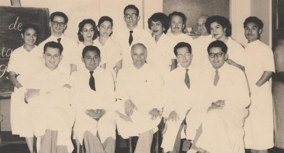 Grupo médico del hospital Obrero, en 1956. Sentados de izquierda a derecha: doctores Enrique Document, Óscar Valdivia, Carlos Alberto Seguín, Sergio Zapata, Andrés Cáceres. De pie de izquierda a derecha: secretaria Frida Vargas, doctor José Alva, secretaria Alicia Iglesias, enfermera Irene Indiveri, doctor Enrique Ghersi, secretaria Leonor Maturana, enfermero Oswaldo Paredes, enfermero Amancio Martell, secretaria Yolanda Álvarez, auxiliar Quintín-