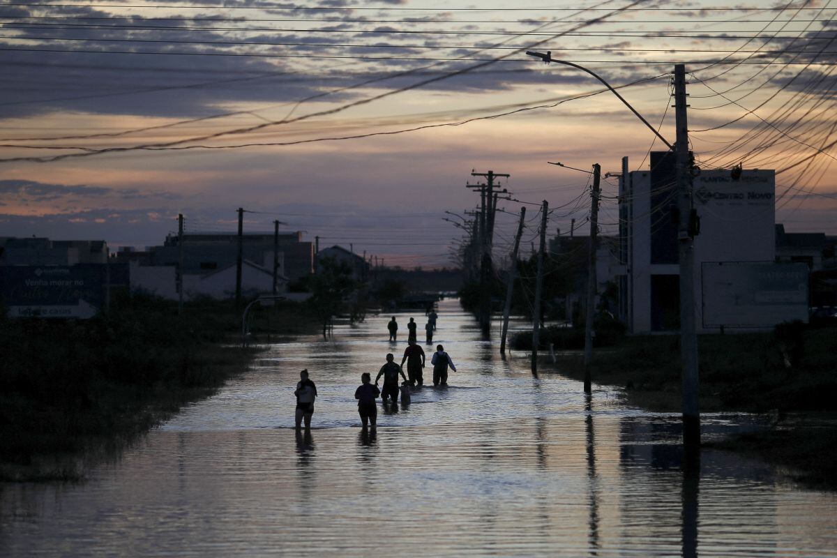 People walk through a flooded street in Eldorado do Sul, Rio Grande do Sul. Around 400 municipalities were affected by the worst natural calamity to ever hit the state of Rio Grande do Sul (Photo: AFP).