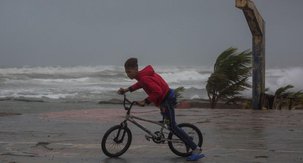 Un joven monta su bicicleta en la playa de Nagua, República Dominicana, el 19 de septiembre de 2022, cuando el huracán Fiona pasa por el país. (Erika SANTELICES / AFP).