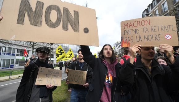 Los manifestantes sostienen pancartas que dicen "No" y "Macron, toma tu jubilación, no la nuestra" durante una manifestación un día después de que el gobierno francés impulsara una reforma de las pensiones en el parlamento sin votación, utilizando el artículo 49.3 de la constitución, en Rennes, oeste de Francia. el 17 de marzo de 2023. (Foto de JEAN-FRANCOIS MONIER / AFP)