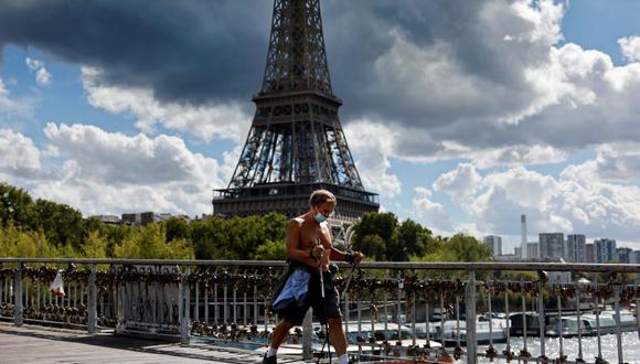 Un hombre que usa mascarilla protectora pasa por delante de la Torre Eiffel en París el 28 de agosto de 2020. (Foto de Thomas COEX / AFP).